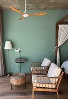 Una habitación con ventilador de techo, muebles de mimbre, una lámpara y un radio en la pared.