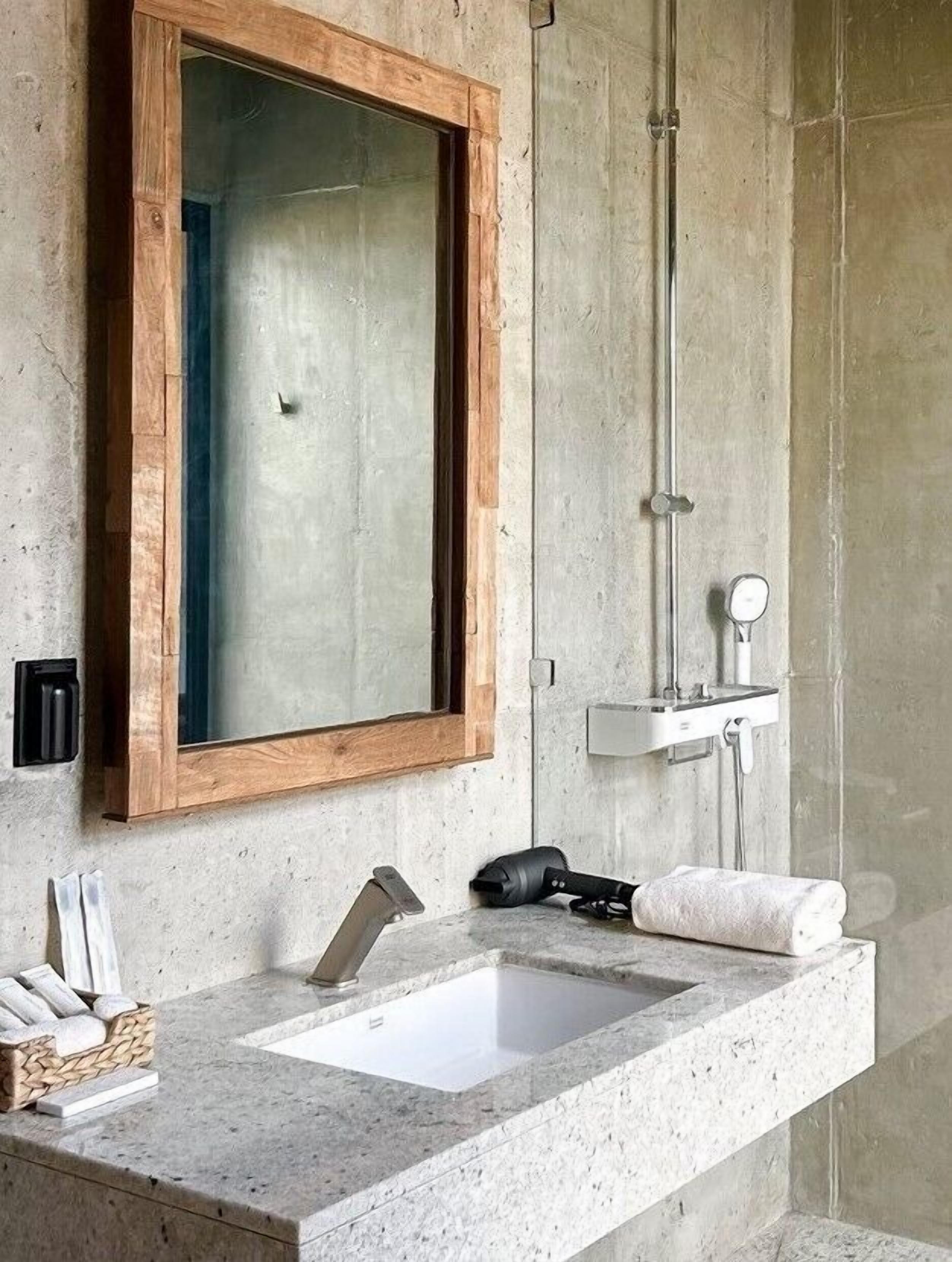 A bathroom with a wooden-framed mirror, a sink, and a shower.