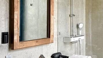 A bathroom with a wooden-framed mirror, a sink, and a shower.