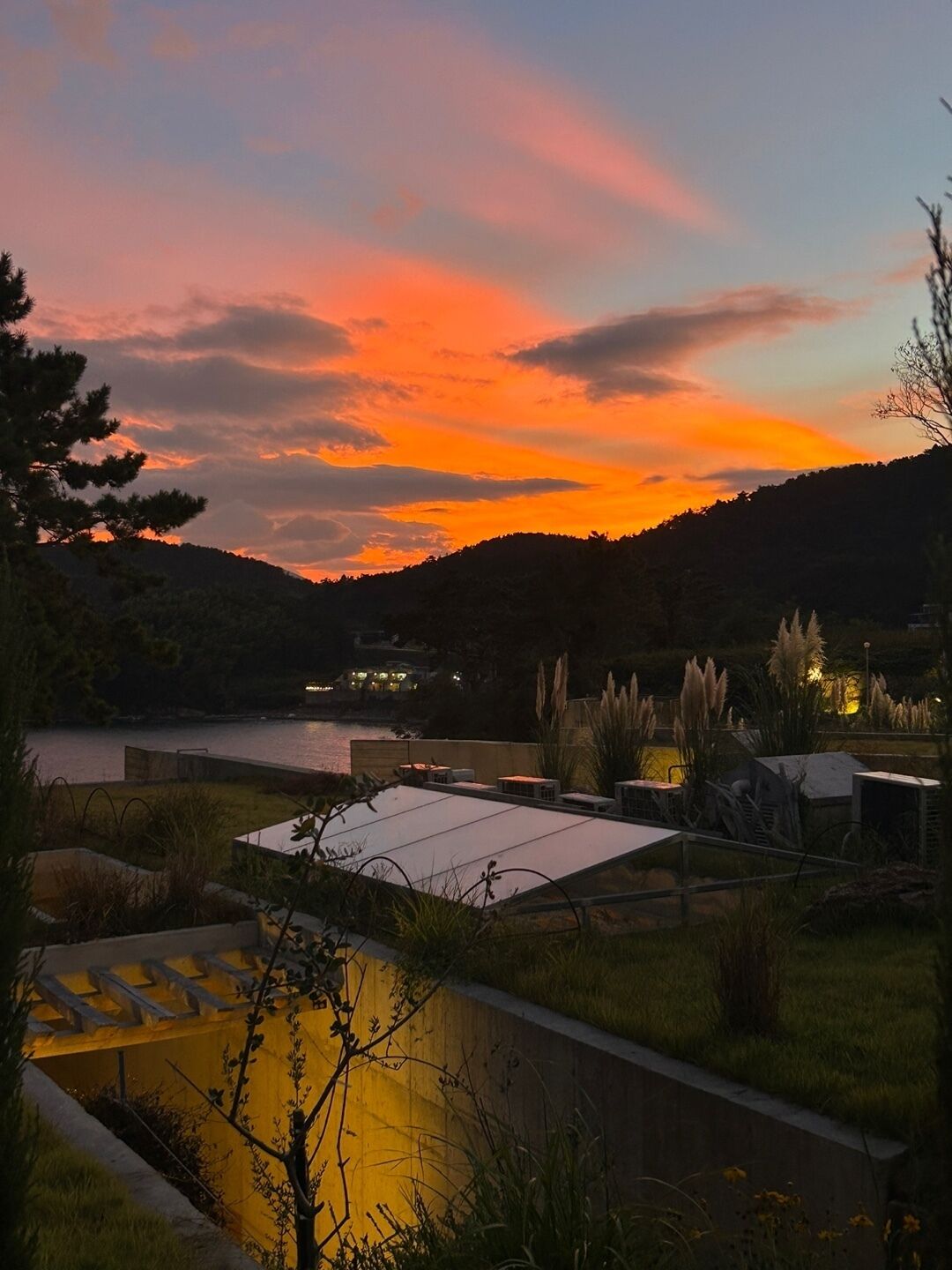 Eine Dachterrasse mit Blick auf einen See und Hügel bei Sonnenuntergang.