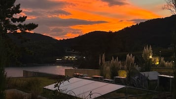 Eine Dachterrasse mit Blick auf einen See und Hügel bei Sonnenuntergang.
