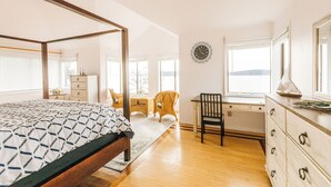 A bedroom with a four-poster bed, a desk, and a chair.