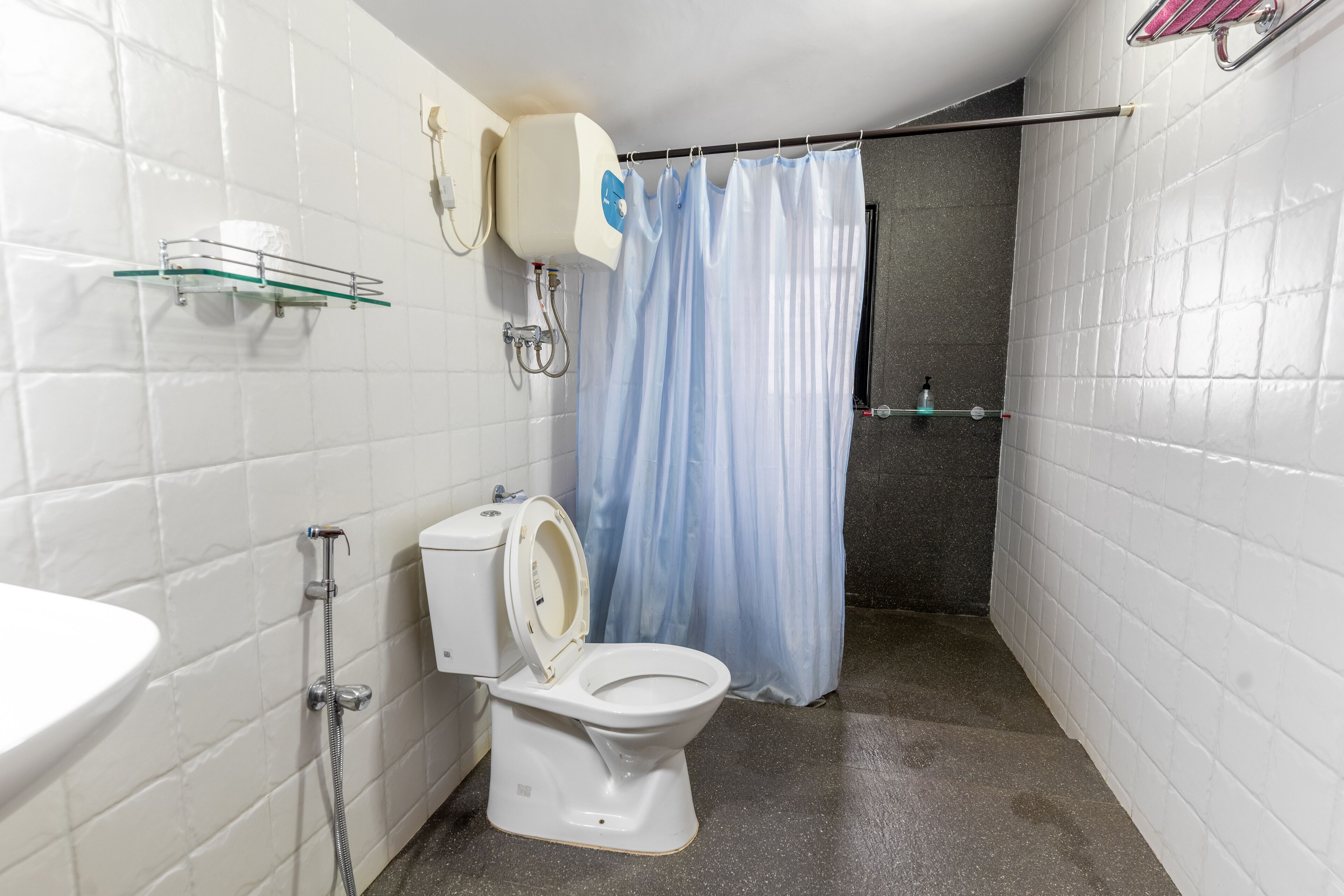 A bathroom with a toilet, a shower, and a sink.