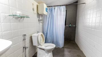 A bathroom with a toilet, a shower, and a sink.