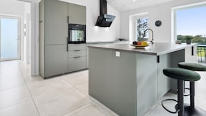 Een moderne keuken met een centraal eiland, inbouwapparatuur en een groot raam met uitzicht.