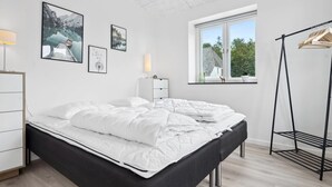 Een moderne slaapkamer met een bed, een dressoir, een raam met uitzicht en wanddecoratie.