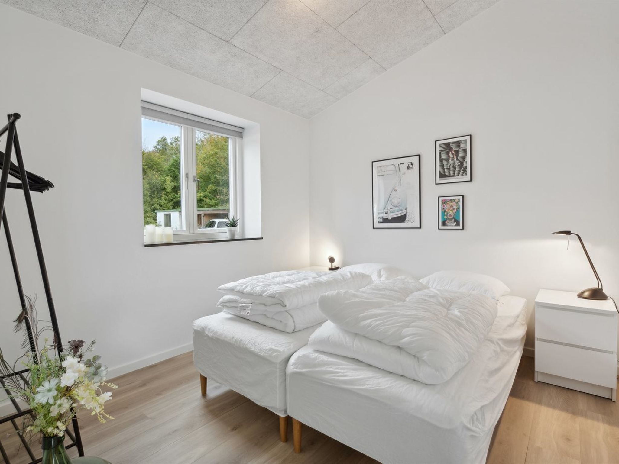 Quarto moderno com cama, mesas de cabeceira, janela e obras de arte na parede.