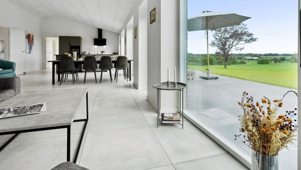 Een moderne woonkamer met een eethoek, grote ramen en uitzicht op het landschap.