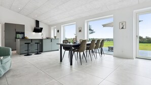 Een moderne keuken met een eethoek, grote ramen en uitzicht op de omgeving.