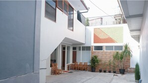 A modern two-story building with a covered patio area featuring outdoor seating and potted plants. - Hotel O 111 Residence (Batu)