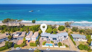 Un quartier résidentiel situé sur la côte, avec des maisons, une piscine et une vue sur l’océan.