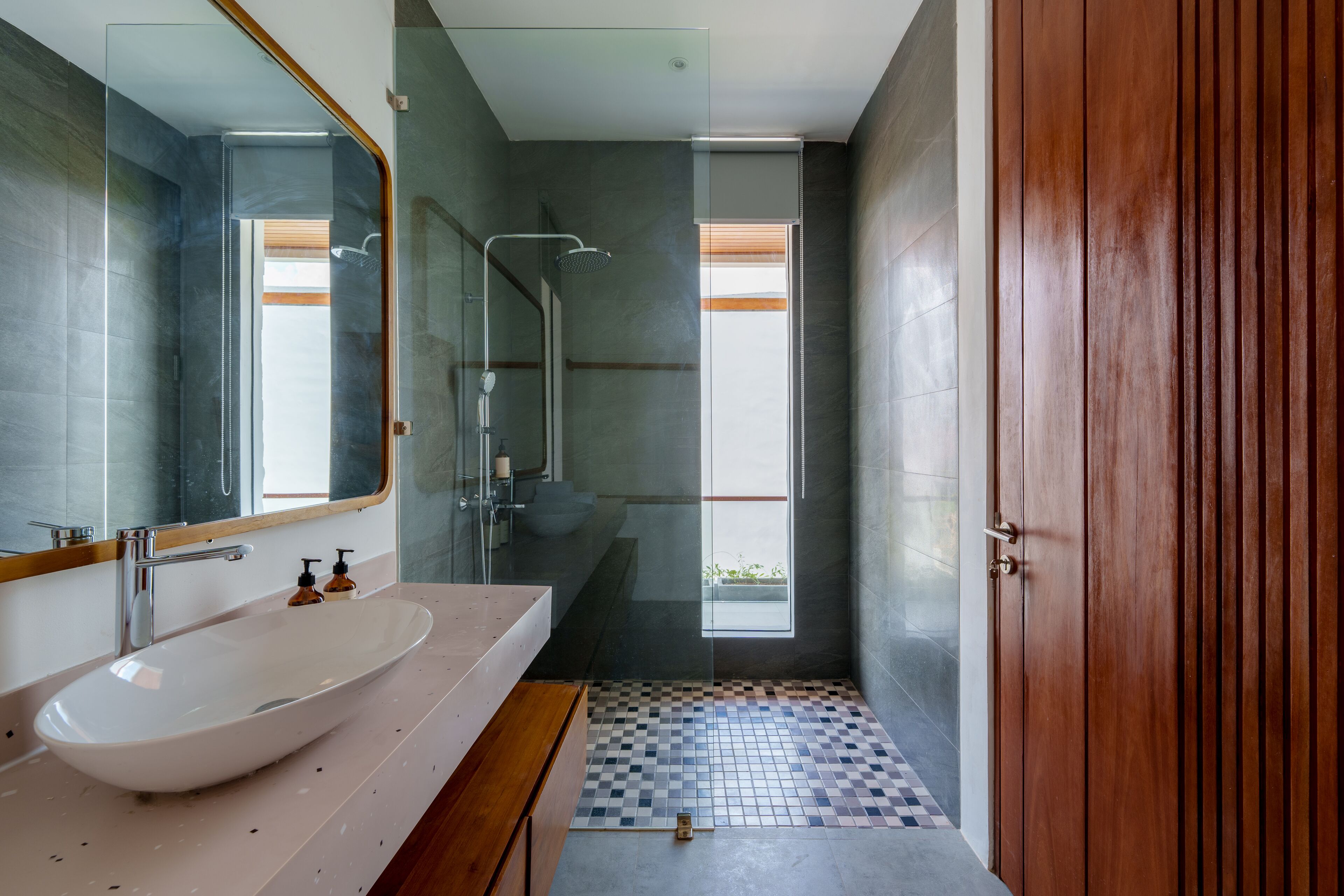 A modern bathroom with a large mirror, a white sink, and a shower area.