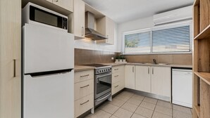 Una cocina moderna con armarios blancos, horno empotrado, microondas y lavavajillas.