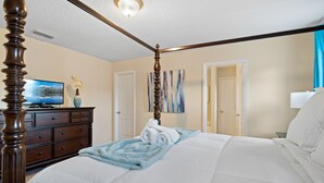 A bedroom with a four-poster bed, a dresser, a television, and a painting on the wall.
