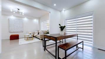 Amplia sala de estar con una mesa de centro de madera, un sofá y un reposapiés rojo.