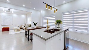 A modern kitchen with a central island, white cabinetry, and a pendant light fixture. - GLOBALSTAY 4-Bd House Near Lake Simcoe (Georgina)