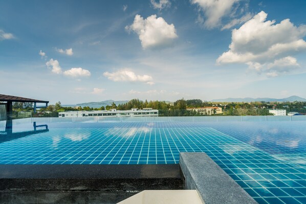 A large outdoor swimming pool with a clear blue sky and distant mountains.