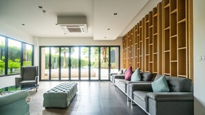 Una sala moderna con un sofá gris, un sillón verde y una estantería de madera.