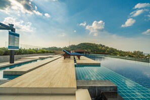 A pool area with a wooden deck, lounge chairs, and a signboard.