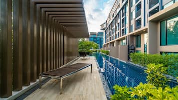 A modern outdoor pool area with a wooden bench and a metal railing.