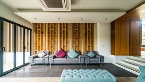 Una sala moderna con sofá modular, otoman y mueble de pared de madera.