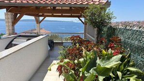 En balkong med en pergola, krukväxter och utsikt över havet.