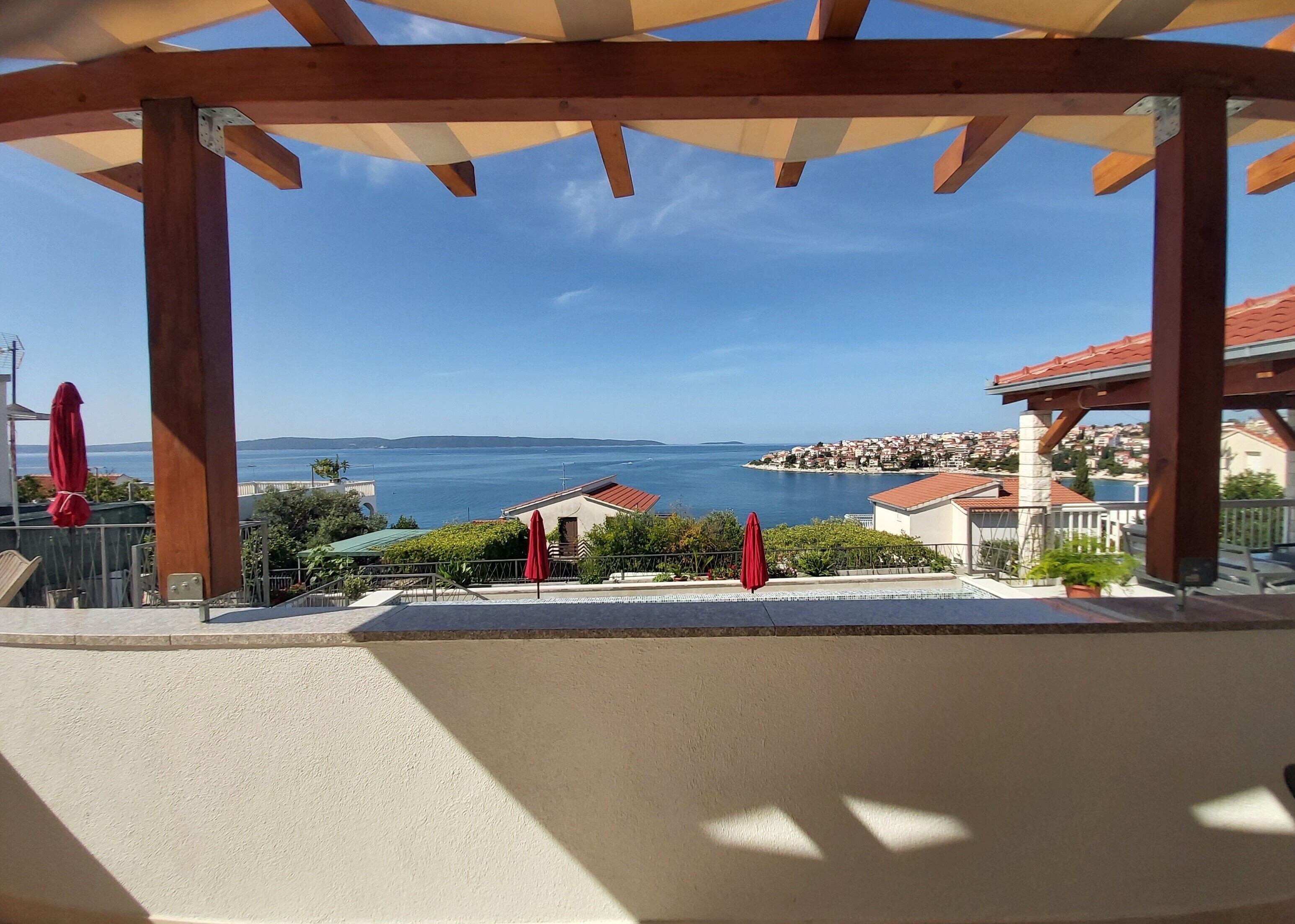 A covered outdoor area with a view of the sea and a town in the distance.