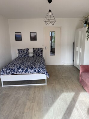 A bedroom with a bed, a wardrobe, a door, and a hanging light fixture.