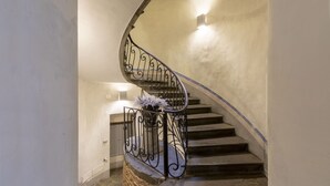 A spiral staircase with a wrought iron railing and a vase of white flowers at the bottom.