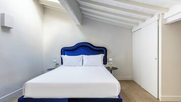 Ein Schlafzimmer mit Bett, Nachttischen, einem Kleiderschrank und einer geneigten Decke.