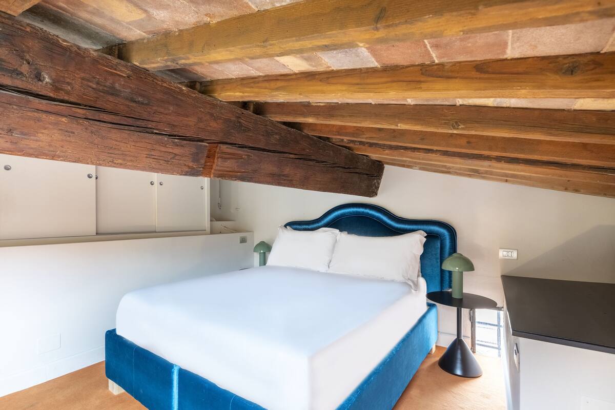 A bedroom with a bed, a nightstand, a lamp, and a wardrobe.