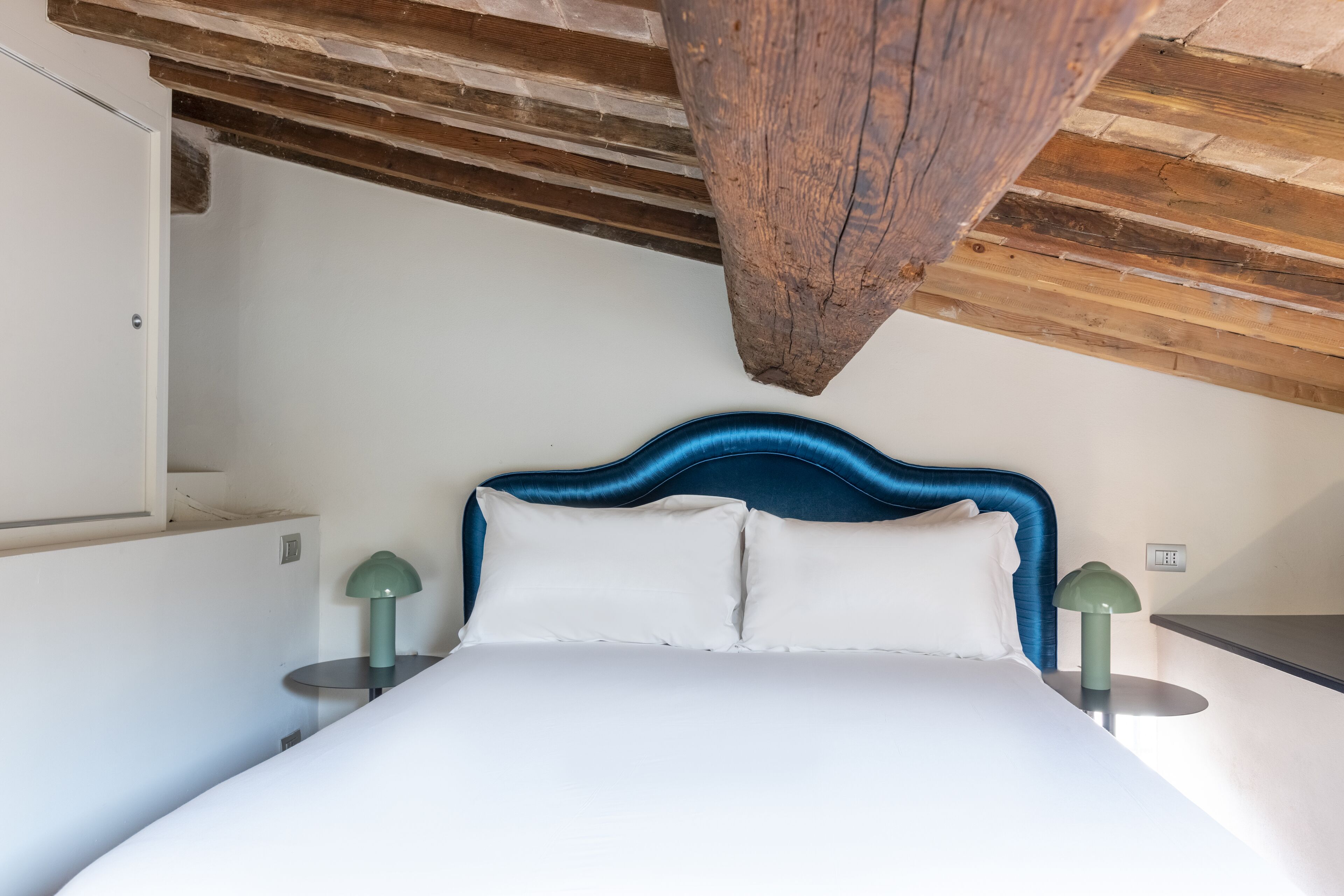 A bedroom with a large bed, a wooden ceiling, and two bedside tables with lamps.
