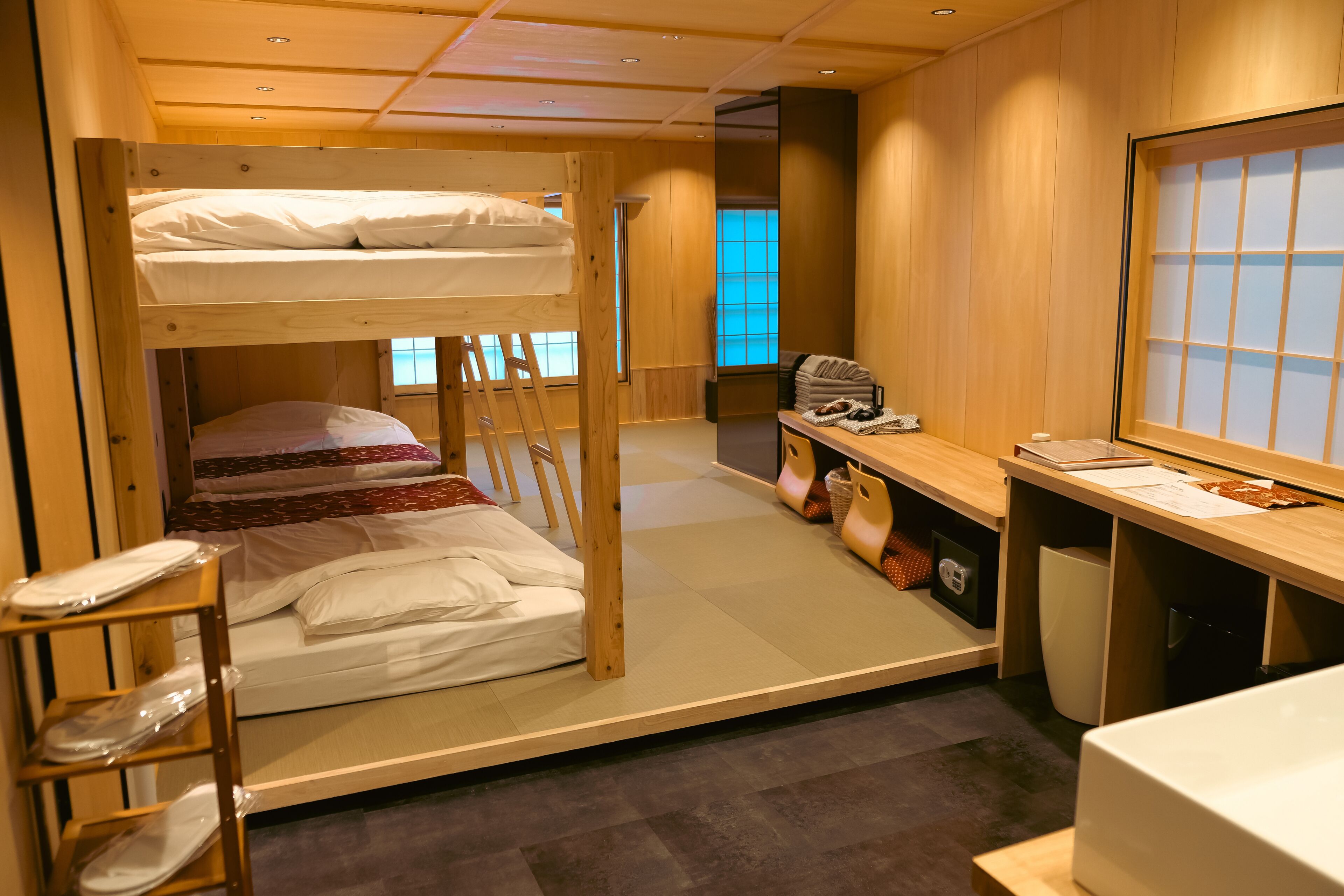 A bunk bed room with a desk, chair, and a window.