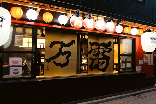 Un restaurante con decoración japonesa tradicional, que incluye faroles y caligrafía en el ventanal.