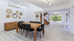 A spacious dining area with a wooden table and chairs, a wooden cabinet, and decorative mirrors on the wall.