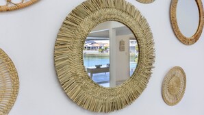 A round woven mirror with a view of a pool and outdoor seating area.