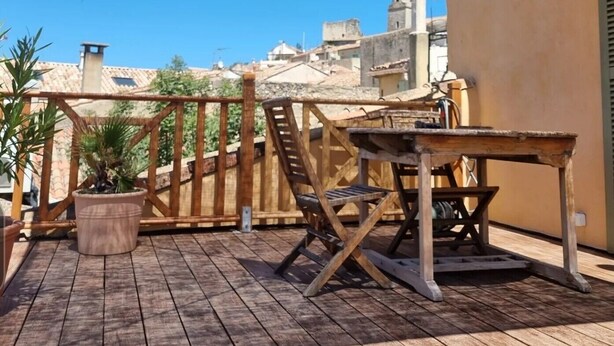 A wooden deck with a table and chairs, a potted plant, and a large woven shade structure. - Apartment 'Gîte Durance' with Mountain View, Wi-Fi and Air Conditioning (Mallemort)