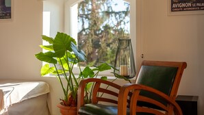 A room with a window, a chair, a potted plant, and a candle holder. - Apartment 'Gîte Durance' with Mountain View, Wi-Fi and Air Conditioning (Mallemort)