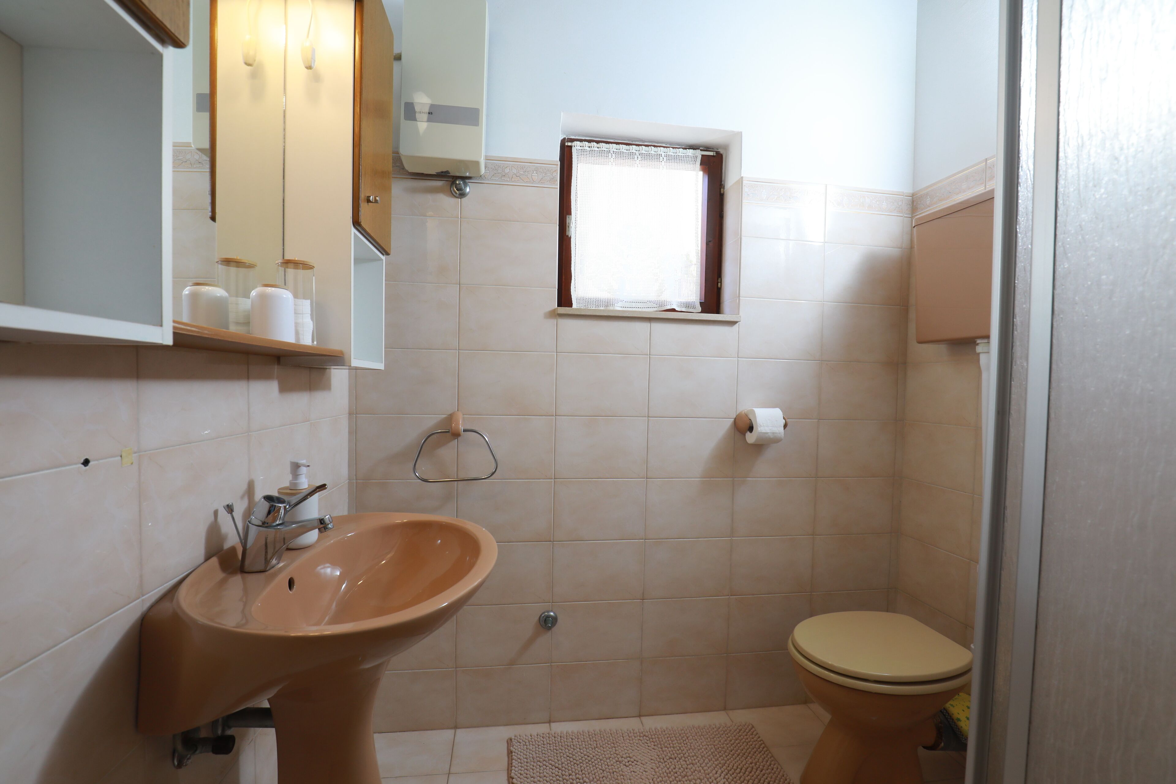 Een badkamer met een wastafel, toilet en een klein raam.