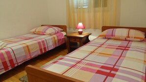 A bedroom with two single beds, a nightstand with a lamp, and a window with curtains. - Heated infinity pool, family apartment with panoramic sea view a1 (Okrug Gornji)