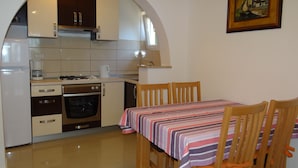 A compact kitchen with a dining area, a stove, oven, and a coffee maker. - Heated infinity pool, family apartment with panoramic sea view a1 (Okrug Gornji)