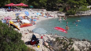A beach with people sunbathing, swimming, and using umbrellas. - Heated infinity pool, family apartment with panoramic sea view 2 (Okrug Gornji)