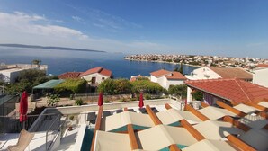 A rooftop terrace with a pool, overlooking a coastal town and the sea. - Heated infinity pool, family apartment with panoramic sea view 2 (Okrug Gornji)