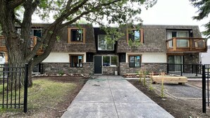 A modern two-story building with a stone facade, large windows, and a central entrance. - One Bedroom Condo Near Whyte Ave (Edmonton)