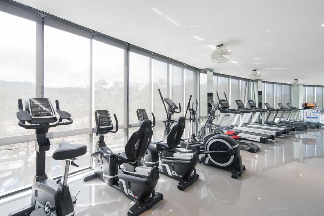 Une salle de sport équipée de vélos d’appartement, de machines elliptiques et de tapis de course, disposés en rangées.