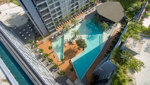 Un hotel de altura con varios balcones, una piscina central y abundante vegetación.