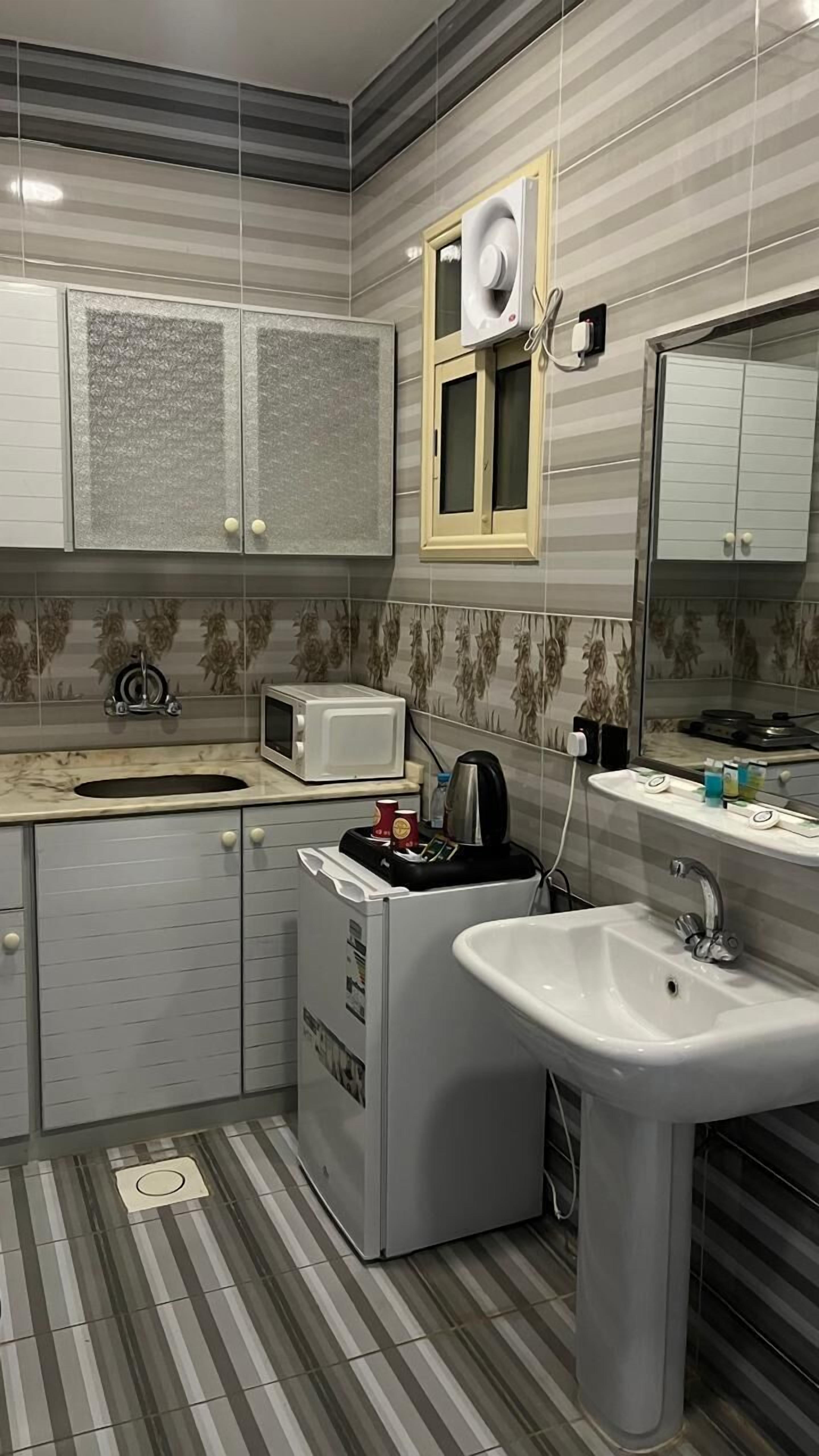 A compact kitchen with a microwave, kettle, and sink.