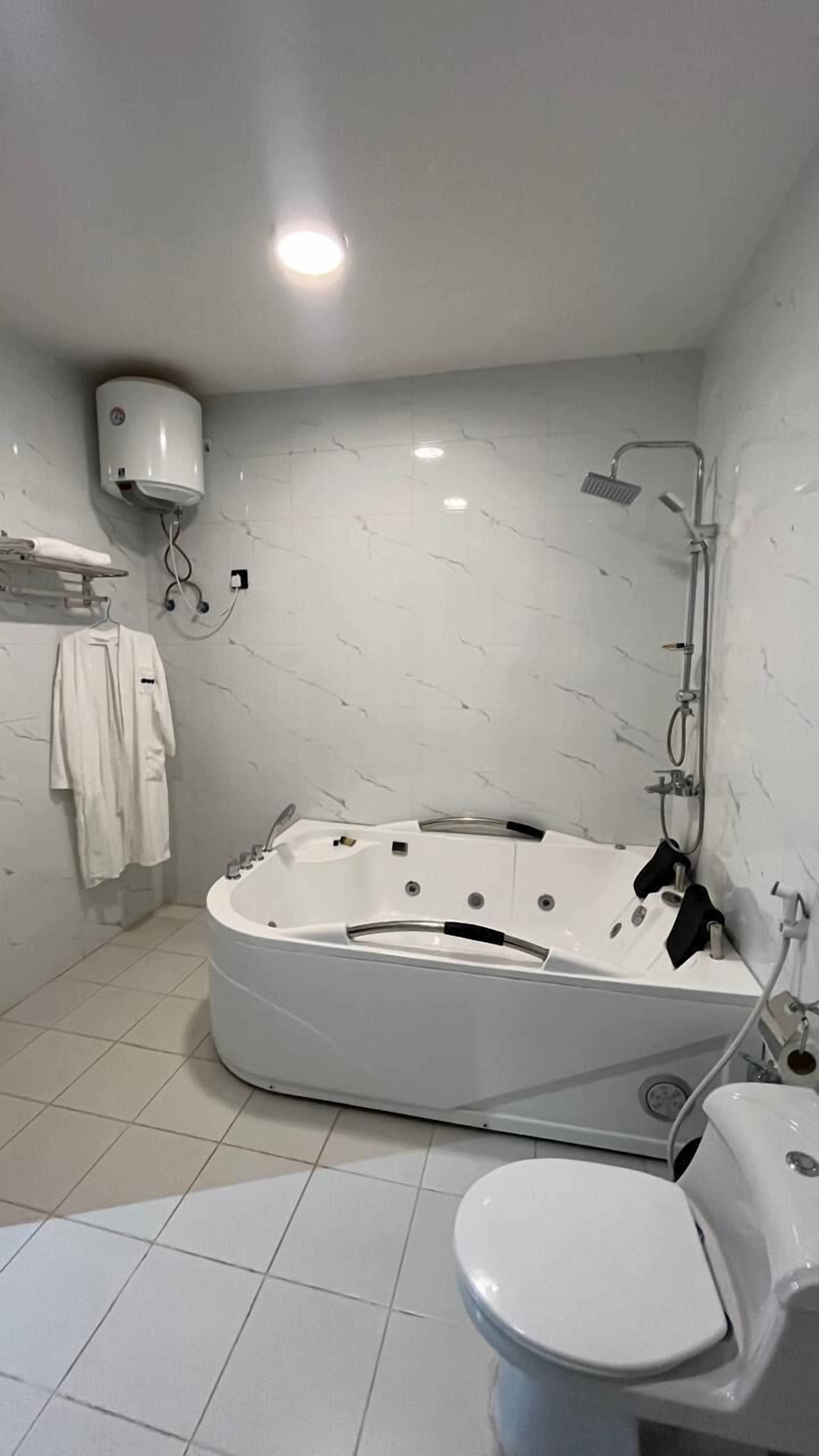 Un baño moderno con una bañera independiente, un inodoro y un perchero con toallas.