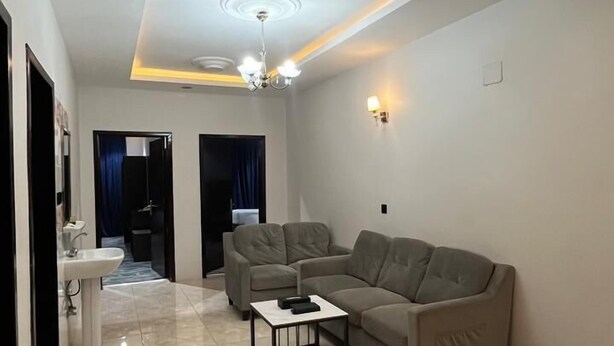 A modern living room with a beige sofa, a coffee table, and a chandelier. - QIMAM PARK 4 Abha (Abha)