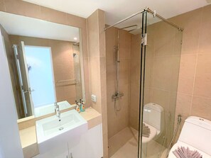 Une salle de bain moderne avec une douche à parois de verre, un lavabo blanc et des toilettes.
